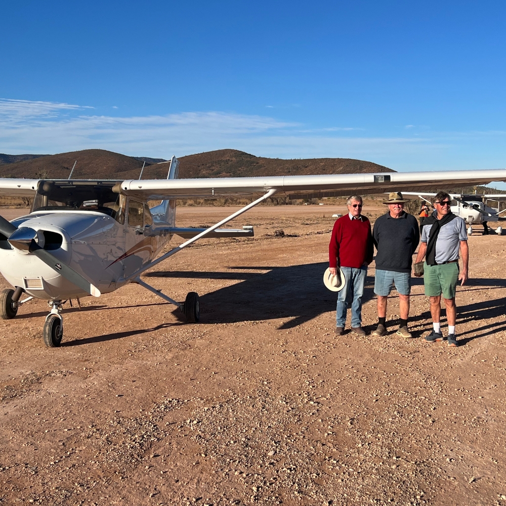 A small group of guests beside the aircraft on an outback strip